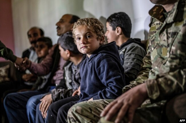 FILE - Iraqi Yazidi children rescued from the Islamic State (IS) group wait to board buses bound for Sinjar in Iraq's Yazidi heartland, April 13, 2019.