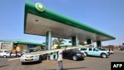 FILE - A man carries goods past a gas station in Lilongwe, Malawi, July 14, 2011. 