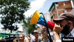 Un hombre sostiene un megáfono con la bandera de Venezuela durante un mitin político opositor antes de las elecciones regionales de noviembre, en Caracas, el 19 de agosto de 2021.