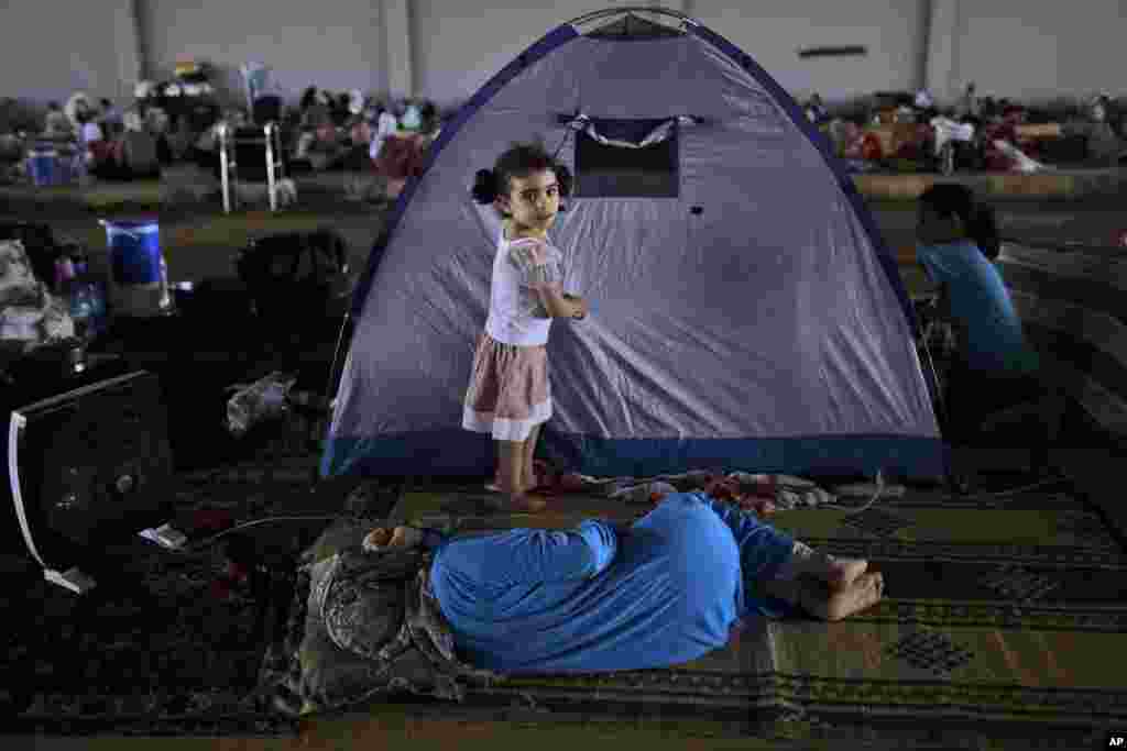 Syrian girl, Raghad Hussein, 3, who fled her home with her family due to fighting between the Syrian army and the rebels, stands by her family's makeshift tent, near Azaz, Syria, Aug. 26, 2012.