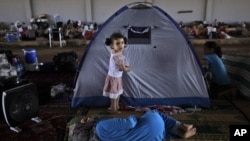 Syrian girl, Raghad Hussein, 3, who fled her home with her family due to fighting between the Syrian army and the rebels, stands by her family's makeshift tent, near Azaz, Syria, Aug. 26, 2012.