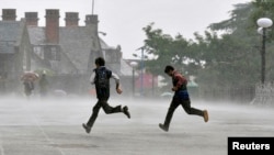 Men run for cover during a heavy rain shower in the northern Indian hill town of Shimla, July 4, 2014.