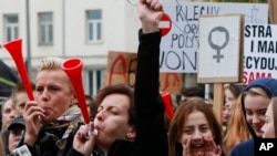 Polish women and some male supporters blow horns while raising a hanger, the symbol of illegal abortion, during a nationwide strike and demonstration to protest a legislative proposal for a total ban on abortion in Warsaw, Oct. 3, 2016. 