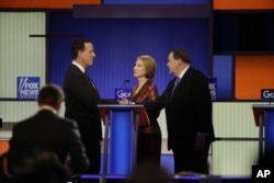 Rick Santorum, Carly Fiorina and Mike Huckabee talk after a Republican presidential primary debate in Des Moines, Iowa, Jan. 28, 2016.