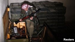 A Free Syrian Army fighter checks weapons which were seized at the army base in Hawa village, north Aleppo, December 23, 2012. 