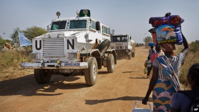 FILE - Displaced people are passed by a United Nations vehicle while walking towards a U.N. camp in Malakal, South Sudan, Dec. 30, 2013.