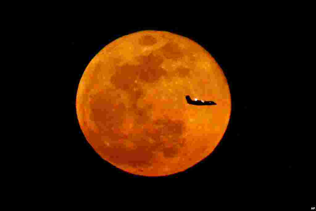 A plane descending into Newark Liberty International Airport crosses over the full moon rising seen from Eagle Rock Reservation&nbsp;in West Orange, New Jersey, March 23, 2016.