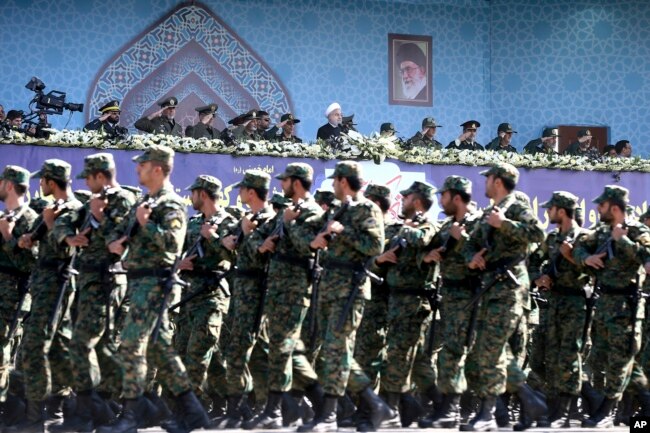 FILE - Iran's President Hassan Rouhani, top center, reviews army troops marching during the 37th anniversary of Iraq's 1980 invasion of Iran, in front of the shrine of the late revolutionary founder, Ayatollah Khomeini, just outside Tehran, Iran.