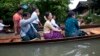 Myanmar opposition leader Aung San Suu Kyi, center, rides a boat on her way to a monastery where flood victims are sheltered, in Bago, northeast of Yangon, Myanmar, Aug. 3, 2015.