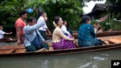 Pemimpin oposisi Myanmar Aung San Suu Kyi (tengah) naik perahu dalam perjalanan ke sebuah biara yang menjadi tempat penampungan bagi para korban banjir, di Bago, 80 kilometer (50 mil) timur laut dari Yangon, Myanmar, (3 Agustus 2015).