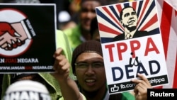 Protestors wave placards at a rally against the Trans Pacific Partnership (TPP) just days before parliament is due to open a debate on the free trade pact in Kuala Lumpur, Malaysia, January 23, 2016. 