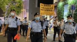军装警员64日晚在铜锣湾渣甸坊一带举牌警告，驱散聚集悼念六四市民。(美国之音汤惠芸)