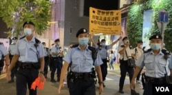 军装警员64日晚在铜锣湾渣甸坊一带举牌警告，驱散聚集悼念六四市民。(美国之音汤惠芸)