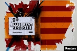A damaged sticker of a Spanish and Catalan flag and a placard reading "Freedom to Jordis!" in reference to leaders of two of the largest Catalan separatist organizations, Catalan National Assembly's Jordi Sanchez and Omnium's Jordi Cuixart, who were jailed by Spain's High Court, are seen in Barcelona, Oct. 22, 2017.