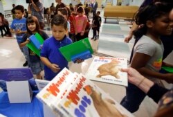 In this Tuesday, Nov. 14, 2017, file photo, students line up for school supplies, including pencils and books that were handed out at Riverdale Elementary School, in Orlando, Fla. (AP Photo/John Raoux)