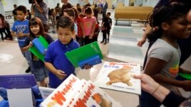 In this Tuesday, Nov. 14, 2017, file photo, students line up for school supplies, including pencils and books that were handed out at Riverdale Elementary School, in Orlando, Fla. (AP Photo/John Raoux)