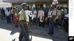 A Zimbabwean policeman patrols near supporters of the Movement for Democratic Change (MDC) 17 Feb. 2009 outside the entrance of Mutare Magistrates court east of Harare