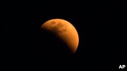 The moon turns a reddish hue as it passes through the earth's shadow during a lunar eclipse as seen in Gauhati, India, Jan. 31, 2018. 