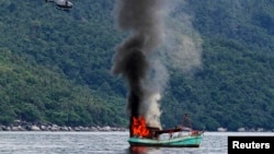 An unmanned Vietnamese fishing boat is blown up and sunk by the Indonesian navy, off the Natuna sea in Anambas, Kepulauan Riau province, Indonesia, Dec. 5, 2014.