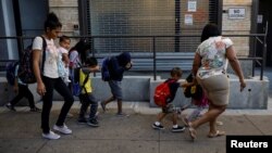 Children cover their faces as they are escorted to the Cayuga Center, which provides foster care and other services to immigrant children separated from their families, in New York City, July 10, 2018. 