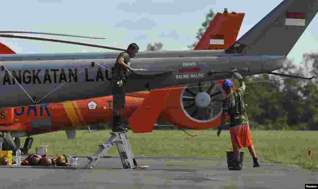 Tentara Indonesia membersihkan ekor helikopter di pangkalan udara Iskandar di Pangkalan Bun, seiring berlanjutnya operasi pencarian pesawat AirAsia bernomor penerbangan 8501 (13/1).