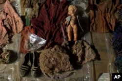 FILE - Clothing, earrings, and a doll that were found among the remains of over 100 Ixil Mayans exhumed from a mass grave, lay on display for hopeful identification by relatives in Santa Avelina, Guatemala, Nov. 29, 2017.