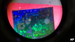 资料照片：在第 21 届中国北京国际高科技博览会上，通过国家控制的清华紫光集团项目展位上设置的显微镜看到的中国微芯片。（美联社2018年5月17日摄。）