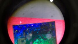A Chinese microchip is seen through a microscope set up at the booth for the state-controlled Tsinghua Unigroup project which is driving China's semiconductor ambitions.