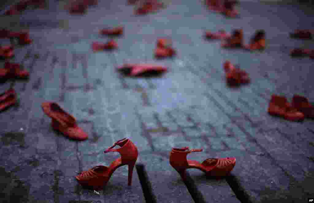 Sepatu-sepatu merah dipajang dalam demonstrasi yang menyoroti kekerasan terhadap perempuan, di lapangan Sant Jaume di Barcelona, Spanyol (21/11). Demonstrasi tersebut merupakan penghormatan untuk para korban femicide (kejahatan kebencian berbasis gender), dengan setiap sepatu mewakili seorang korban kekerasan gender. (AP/Manu Fernandez)