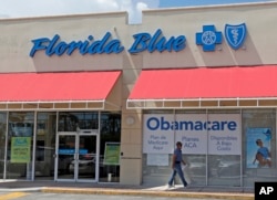FILE - A person walks by a health care insurance office in Hialeah, Florida. National polls in the U.S. have shown voters favored keeping Obamacare, not Republican plans to repeal it.