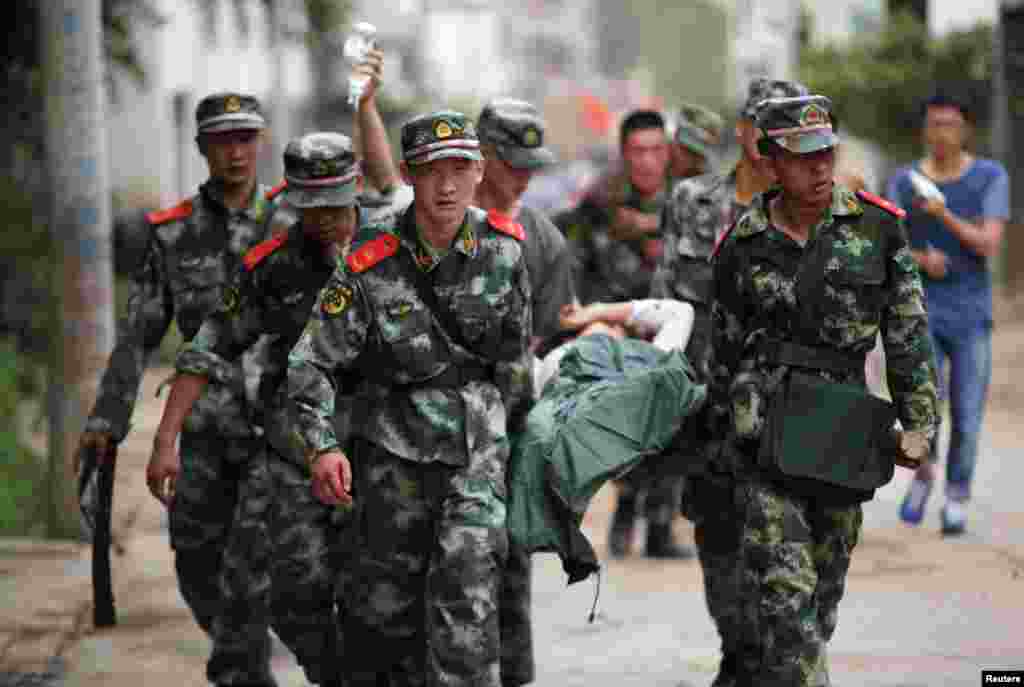 Cảnh sát bán quân sự Trung Quốc khiêng người bị thương trong vụ&nbsp;động&nbsp;đất tại thị trấn Long Đầu Sơn của huyện Lư Điền, tỉnh Vân Nam. &nbsp;