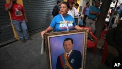 Una mujer sostiene una pintura del presidente Hugo Chávez: el tema de su juramentación también ha regresado a Venezuela.