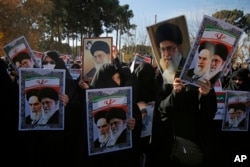 In this photo provided by Tasnim News Agency, women hold posters showing portraits of late Iranian revolutionary founder Ayatollah Khomeini, and Supreme Leader Ayatollah Ali Khamenei during a pro-government rally in the holy city of Qom, Iran, Jan. 3, 2018.