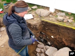 In this Thursday, Nov. 15, 2018, photo archaeologist Sarah Sportman works at a dig site in Wethersfield, Conn.