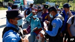 Honduran police check documents of migrants who are part of a caravan hoping to reach the United States, in Corinto, Honduras, Jan. 15, 2022.