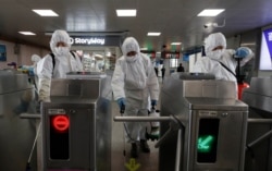 Workers wearing protective gear disinfect as a precaution against the new coronavirus at the subway station in Seoul, South Korea, March 13, 2020.
