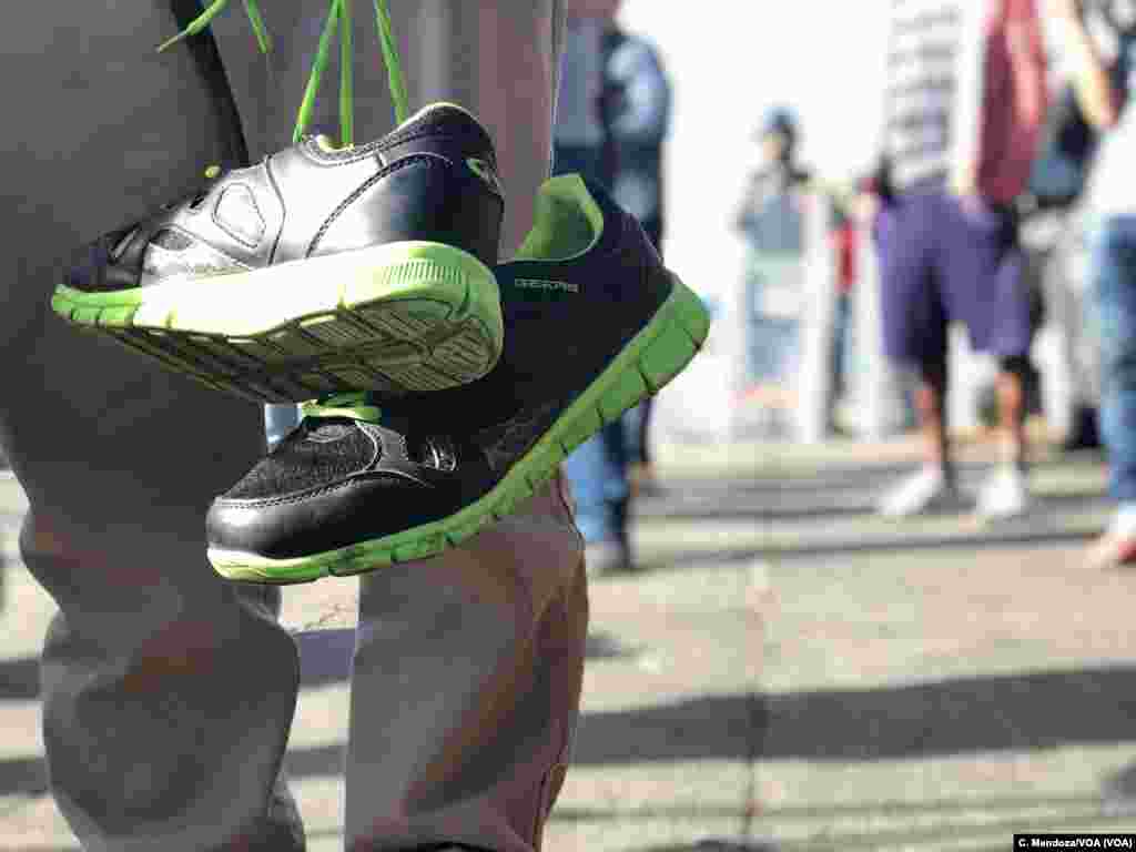 A Honduran migrant carries a second pair of shoes during the caravans march to a pedestrian crossing on Tijuana, Mexico, Nov. 22, 2018. Celia Mendoza/VOA