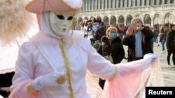 Para pengunjung mengenakan masker wajah di Lapangan Santo Markus setelah hari terakhir karnaval di Venesia, Italia, 24 Februari 2020.