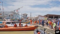 Residents look on as members of National Search and Rescue Agency (BASARNAS) prepare for a search mission for the victims of a ship collision, at a port in Indramayu, West Java, Indonesia, April 4, 2021.