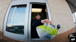 FILE – A fast food restaurant worker hands a patron a salad at a drive up window in Williamsville, New York. 