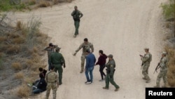 ARCHIVO: Agentes fronterizos y miembros de la Guardia Nacional de Texas detienen a inmigrantes que cruzaron la frontera desde México a EEUU en La Joya, Texas, el 17 de marzo de 2023.