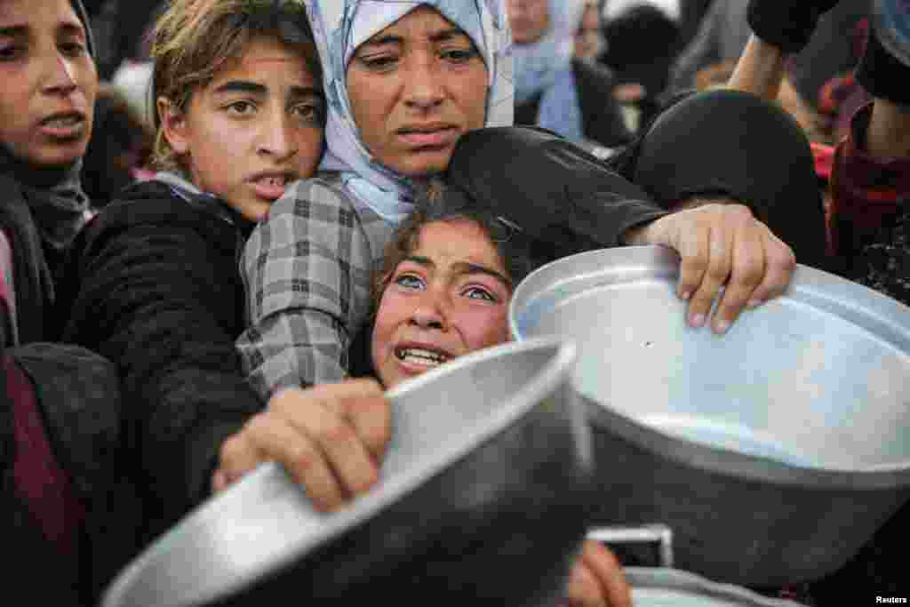 Palestinians gather to receive food cooked by a charity kitchen, before a ceasefire between Hamas and Israel takes effect, in Khan Younis, in the southern Gaza Strip.