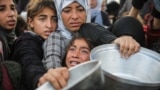 Palestinians gather to receive food cooked by a charity kitchen, before a ceasefire between Hamas and Israel takes effect, in Khan Younis, in the southern Gaza Strip.