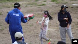 Un miembro de la municipalidad entrega un regalo a una niña de Yaruqui, cerca de Quito, Ecuador, el 1 de junio de 2020.