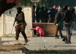 Riot police, carries a pellet air rifle during clashes with anti-government protesters in downtown Baghdad, Iraq, Jan. 30, 2020.