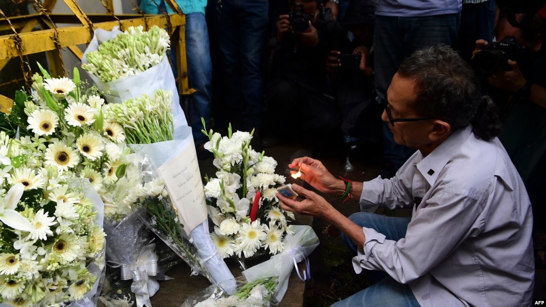 A Bangladeshi social activist lights a candle on floral arrangement that he placed on a road block leading to the Holey Artisan Bakery, the scene of a fatal attack and siege, in Dhaka on July 3, 2016.