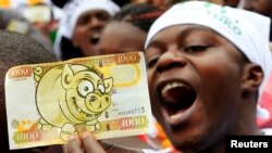 A protester displays a modified Kenyan 1,000 Shilling note ($12) imprinted with an image of a pig to depict what he says is greed in lawmakers demanding for a pay rise, during a demonstration in Nairobi, June 11, 2013.