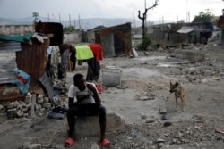 A boy eats next to makeshift shelters at La Saline neighborhood in Port-au-Prince, Haiti, Aug. 8, 2019.