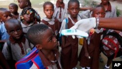 Una maestra usa un termómetro a distancia para tomar la temperatura de los estudiantes en una escuela primaria de Lagos, Nigeria.