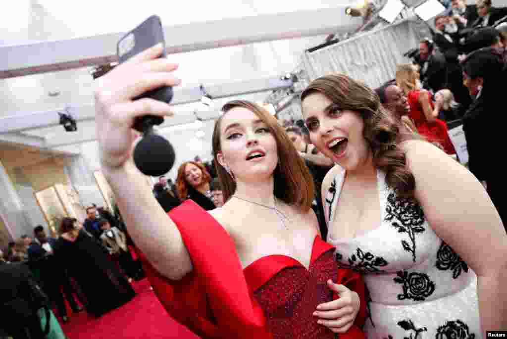 Kaitlin Dever and Beanie Feldstein pose for a selfie on the red carpet during the Oscars arrivals at the 92nd Academy Awards in Hollywood, Feb. 9, 2020. 